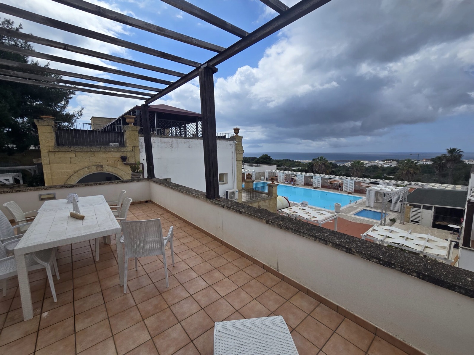 A pergola-shaded terrace overlooking the saltwater pool and the Ionian sea